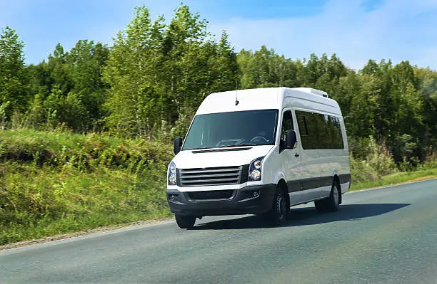 minibus goes on the country highway along the wood