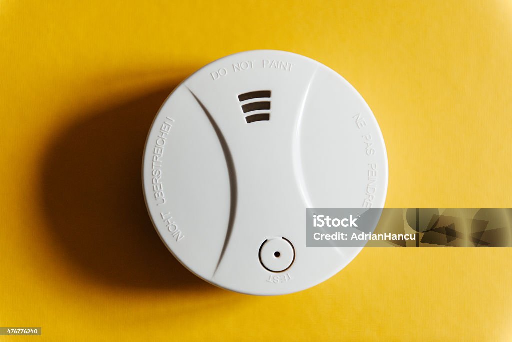 White smoke detector on yellow ceiling White smoke detector on yellow ceiling. A smoke detector is a device that senses smoke, typically as an indicator of fire. Smoke Detector Stock Photo