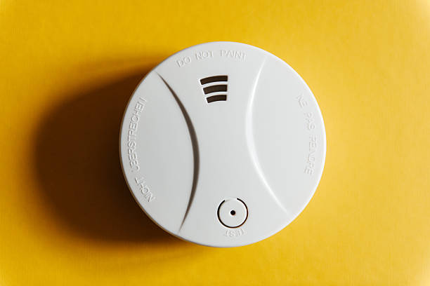 White smoke detector on yellow ceiling White smoke detector on yellow ceiling. A smoke detector is a device that senses smoke, typically as an indicator of fire. smoke detector photos stock pictures, royalty-free photos & images