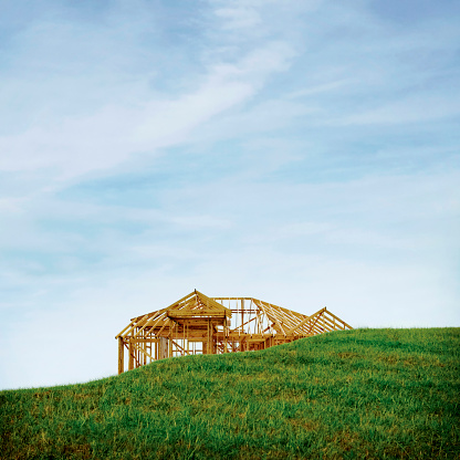 Framed house under construction with grass field in the foreground. Concept composite image.