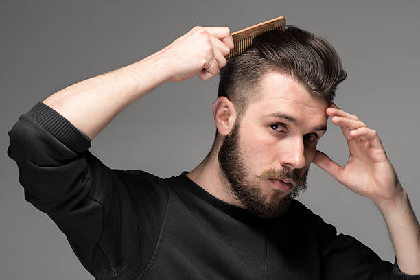 young man comb his hair young man comb his hair on gray background combing stock pictures, royalty-free photos & images