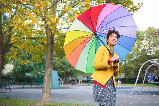 Woman in park with colorful umbrella.