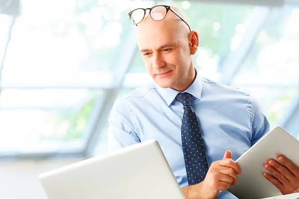 Senior businessman portrait. Portrait of financial manager sitting in front of laptop and calculating financial data.