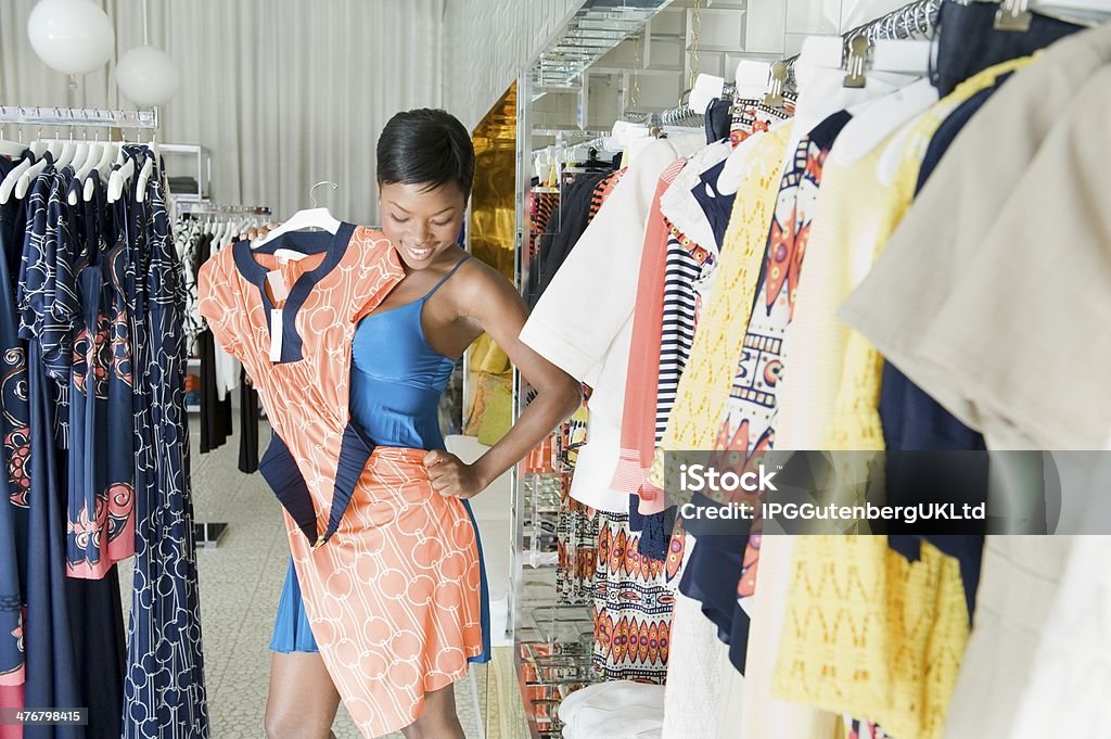 African American female choosing dress at clothing store Happy African American female choosing a dress at clothing store Adult Stock Photo