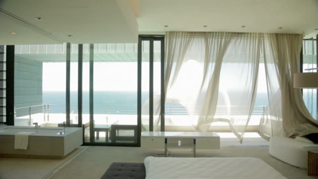 Wind blowing curtain in luxury master bedroom overlooking ocean