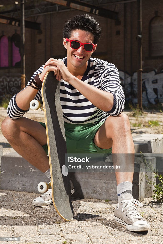 Urbana homem asiático com vermelho e óculos de sol e andar de skate. - Foto de stock de Adulto royalty-free