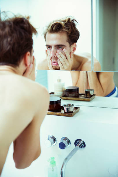 istock Hungover man examining himself in mirror 476806351