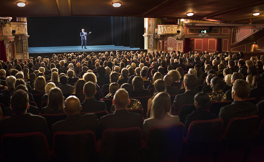 Audience watching performer on stage in theater photo