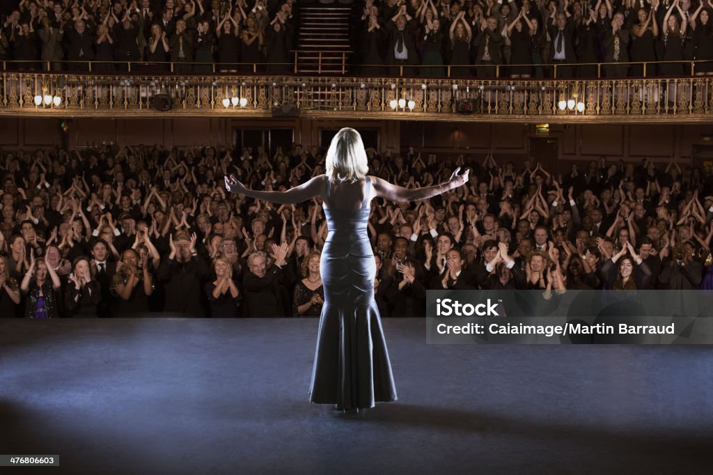 Performer standing with arms outstretched on stage in theater  Stage Theater Stock Photo