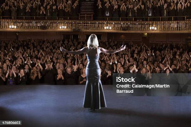 Performer Standing With Arms Outstretched On Stage In Theater Stock Photo - Download Image Now