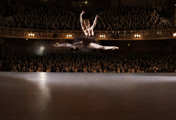 ballet dancer performing on theater stage - skill side view jumping mid air стоковые фото и изображения