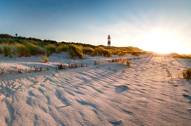 lighthouse list east with sunbeams - duitse noordzeekust stockfoto's en -beelden