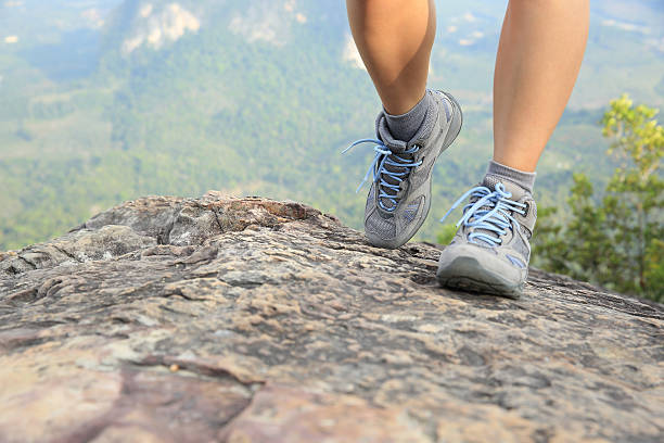 istock woman hiker legs climbing rock at mountain peak 476824072