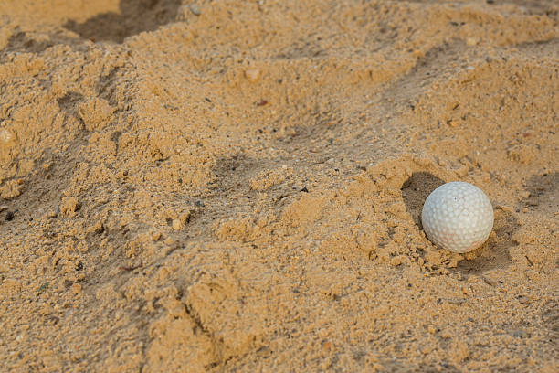 istock Sunlit golf ball with shadow in unraked sand trap. 476824218