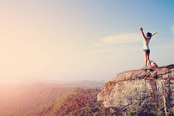 istock cheering young woman hiker open arms at mountain peak 476825552