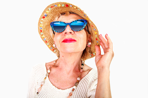 Funny grandma's studio portrait wearing eyeglasses and hat, isolated on white background.