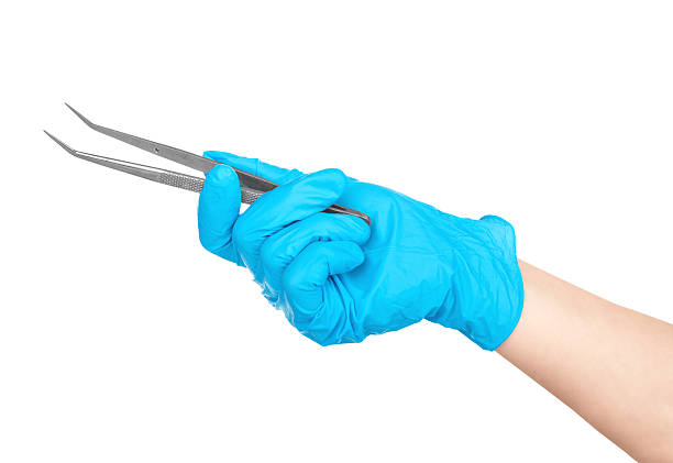 gloved hand holding a medical tweezers isolated on white background gloved hand holding a medical tweezers isolated on white background forceps stock pictures, royalty-free photos & images