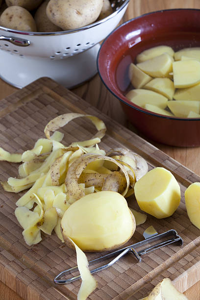 istock Cutting board with potatoes and potato peeler 476836269