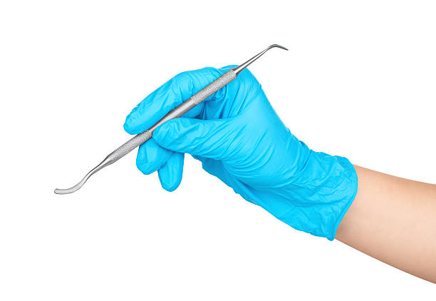 istock Hand in blue glove holding dental tool isolated on white 476836728