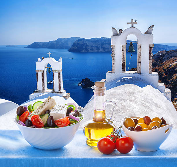 Greek salad in Santorini island, Greece Greek salad in Santorini island against famous windmills, Oia, Greece table ledge stock pictures, royalty-free photos & images