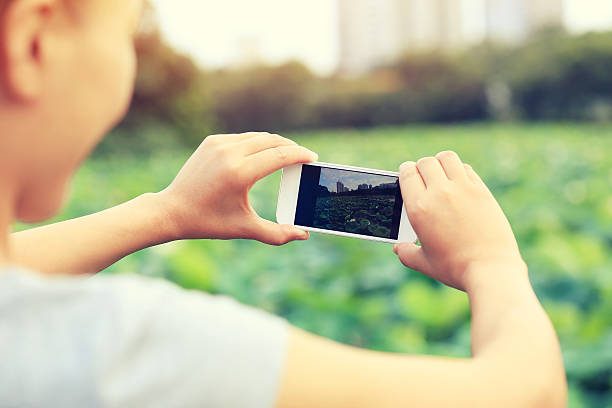 istock young woman taking photo with smart phone 476836886