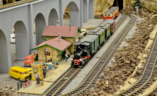 O gauge Passenger train with steam locomotive arrives at the station, pictured from above.