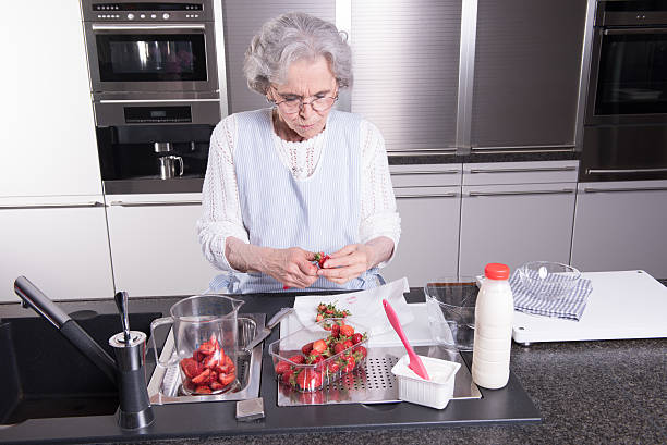 istock Active female pensioner is preparing strawberries in the kitchen 476841560