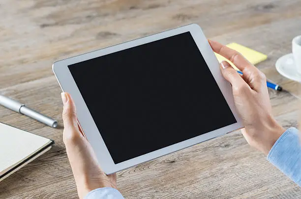 Closeup shot of a woman hand holding digitaltablet. Business woman showing a digital tablet with black screen in her office. Blank screen to put it on your own web page design.