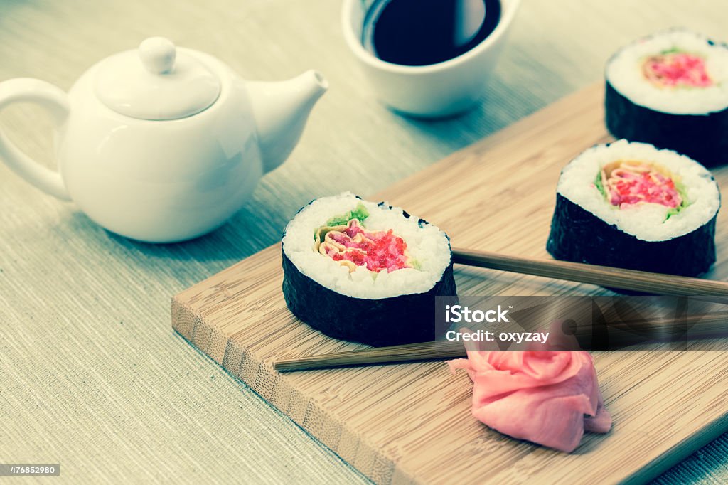 Sushi rolls with ginger, soy sauce and chopsticks Sushi rolls with ginger, soy sauce and chopsticks on wooden desk. Image toned with a retro vintage instagram filter 2015 Stock Photo