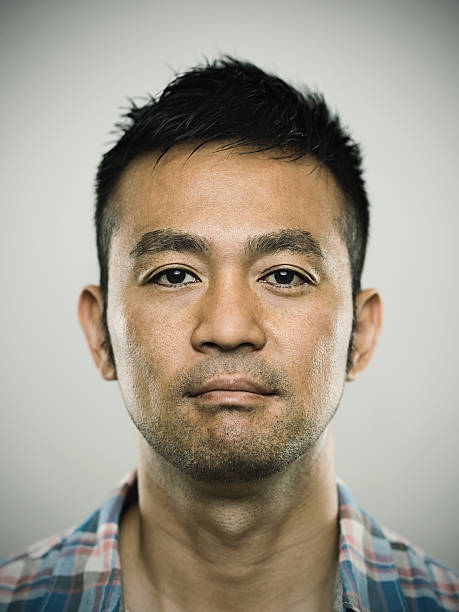Portrait of a young japanese man looking at camera Studio portrait of a japanese young man looking at camera with relaxed expression. The man has around 35 years and has short hair and casual clothes. Vertical color image from a medium format digital camera. Sharp focus on eyes. blank expression photos stock pictures, royalty-free photos & images