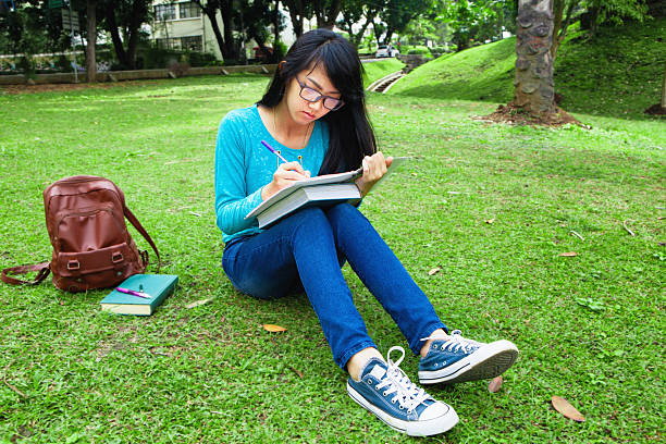 istock College student writing home work outdoor in university 476857056