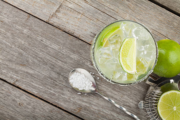 Classic margarita cocktail with salty rim Classic margarita cocktail with salty rim on wooden table with limes and drink utensils margarita stock pictures, royalty-free photos & images