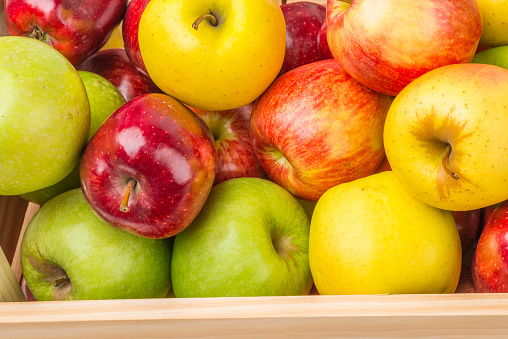 Group of apples in a wooden traditional box. Colorful composition of fruit.