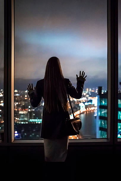the girl looks through the window of the city at night