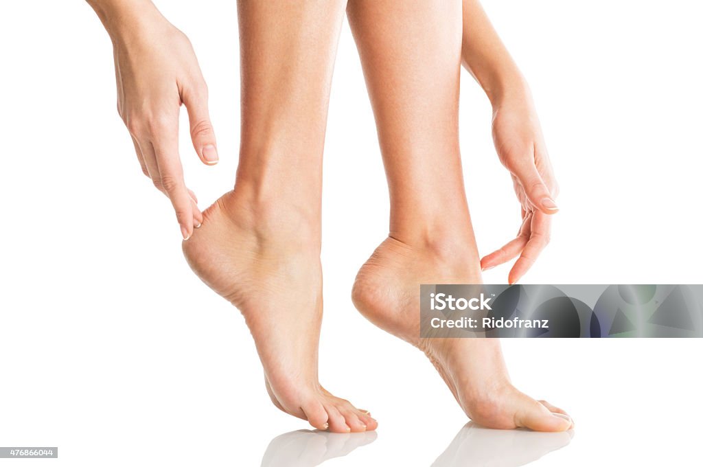 Woman tenderly touches her feet Closeup shot of a woman applying moisturizer to her leg and feet. Beauty feet and hands isolated on white background. Young woman touching hands and legs with french manicured nails. Pedicure Stock Photo