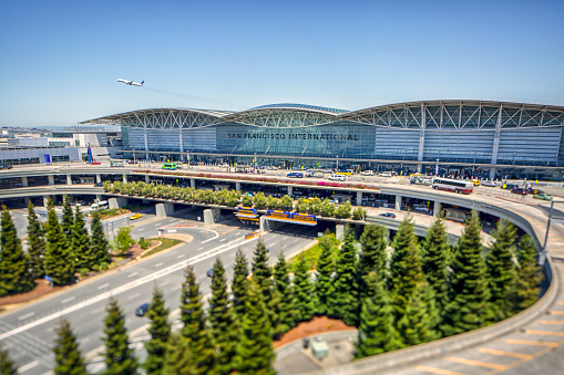 Tilt shift photo of the San Francisco International Airport from a high angle with a commercial airliner taking off.