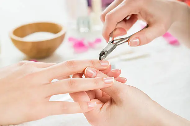 Closeup shot of a woman using a cuticle clipper to give a nail manicure. Woman remove a cuticle nail with nail clipper. Shallow depth of field with focus on cuticle clipper.