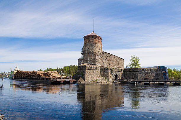 Cargo ship navigating pass Olavinlinna Castle Savonlinna, Finland - May 30, 2015. Shipping company Mopro Oy's vessel m/s Tyrsky pushing a barge called "Vorokki" pass Olavinlinna (St. Olaf's) castle. etela savo finland stock pictures, royalty-free photos & images
