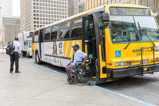 Dallas, Texas, United States - September 13, 2013: An African American man disembarks a public bus using a chair lift in downtown Dallas, Texas.
