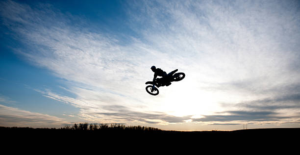 Motocross racer silhouette A motocross racer soaring through the air with a beautiful sunset in the background. air jump stock pictures, royalty-free photos & images