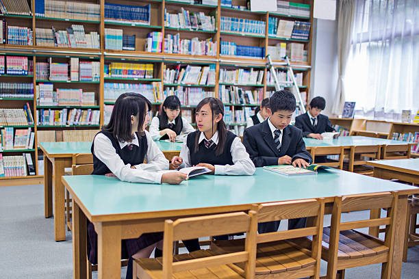 Back view. Female student is in library that full of books. Conception of education.