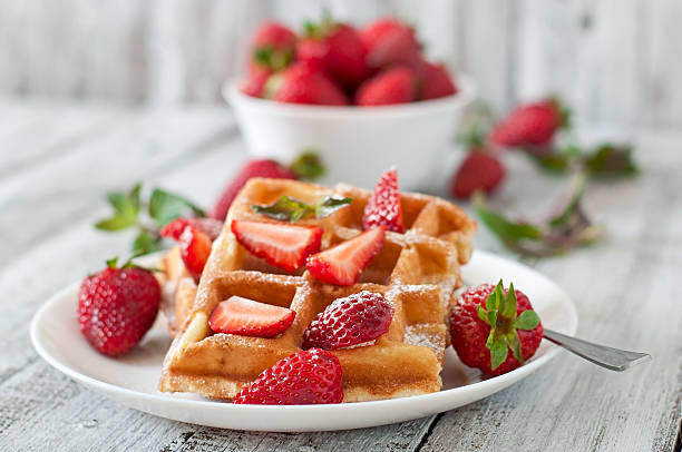 gaufres belges avec des fraises et menthe sur plaque blanche - waffle breakfast syrup food photos et images de collection