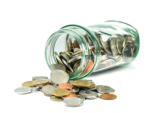 istock Coins spilling out of a glass bottle 476897588