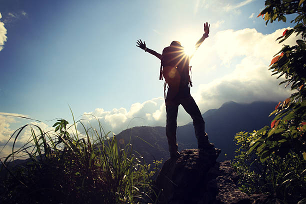 istock cheering woman hiker open arms at mountain peak cliff 476905040