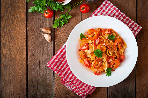 fettuccine ai gamberetti pasta con pomodoro ed erbe aromatiche - prepared shrimp seafood sauces herb foto e immagini stock