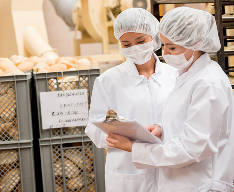 Women working at a food factory and doing inventory on a clipboard