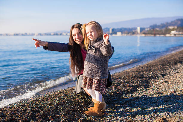 Little girl with mom having fun on the beach in a winter day