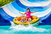 Child with mother on water slide at aquapark