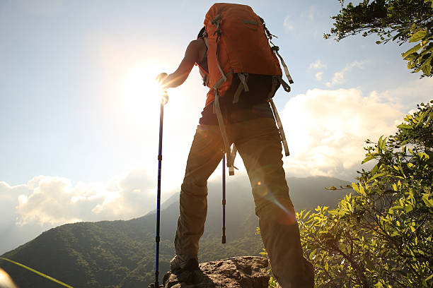 istock cheering woman hiker climbing to mountain peak cliff 476928142