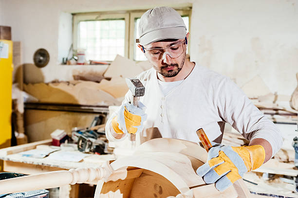istock Carpenter working at a wood table with hammer and chisel. 476932378